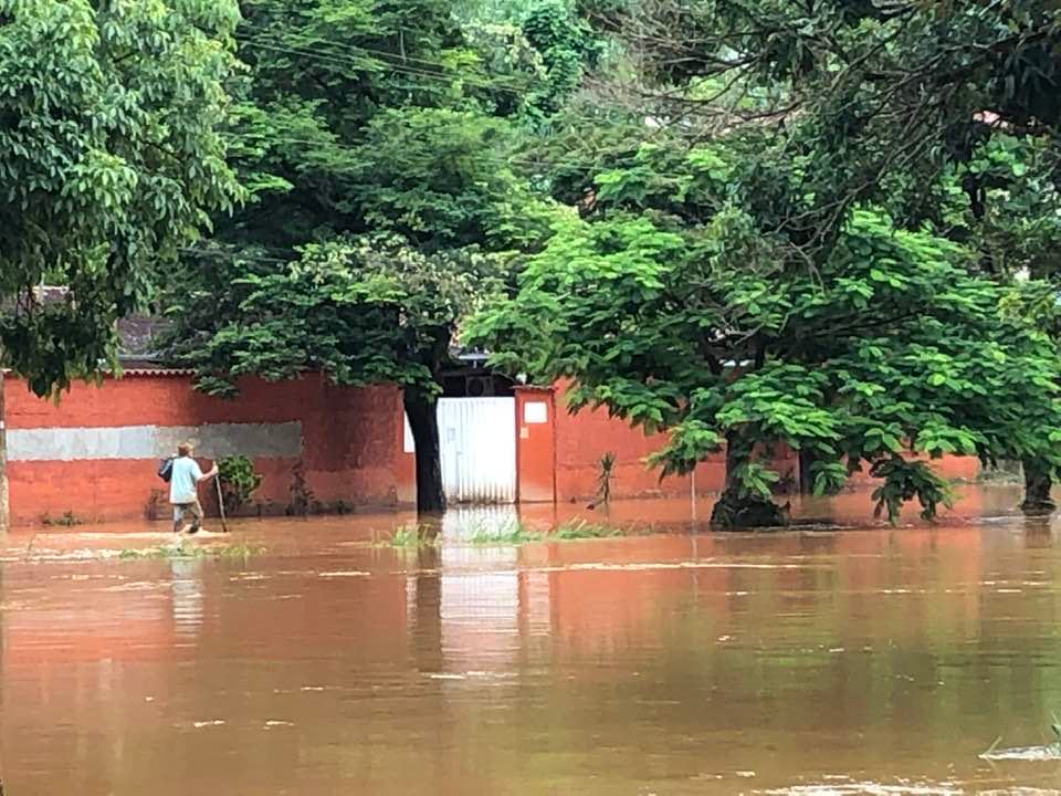 Homem anda na enchente do Rio Jiral pela rua no bairro Conselho em Santa Maria de Itabira