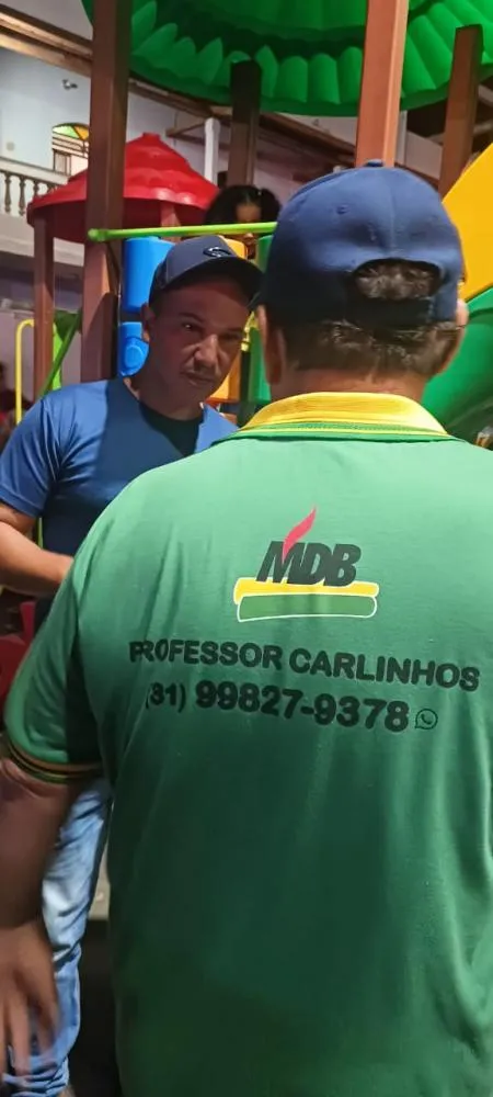  “Prefeito Professor Carlinhos e o vice Geraldo Kilin durante o evento de prestação de contas dos 100 dias de governo, usando a camisa com o número de celular para contato direto com a população.” 